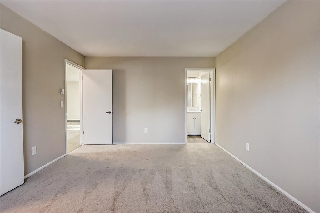 a bedroom with a carpeted floor and a door to a bathroom