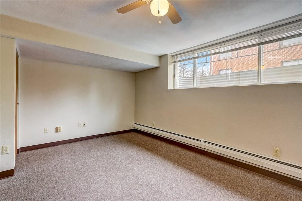 an empty bedroom with a large window and a ceiling fan