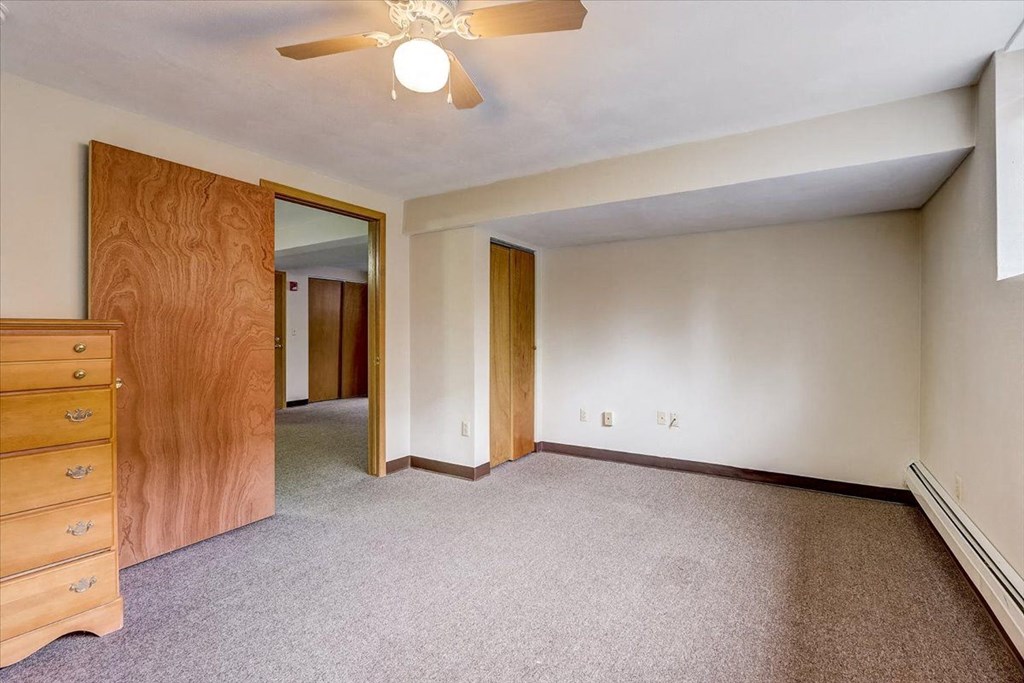 a bedroom with a dresser and a ceiling fan