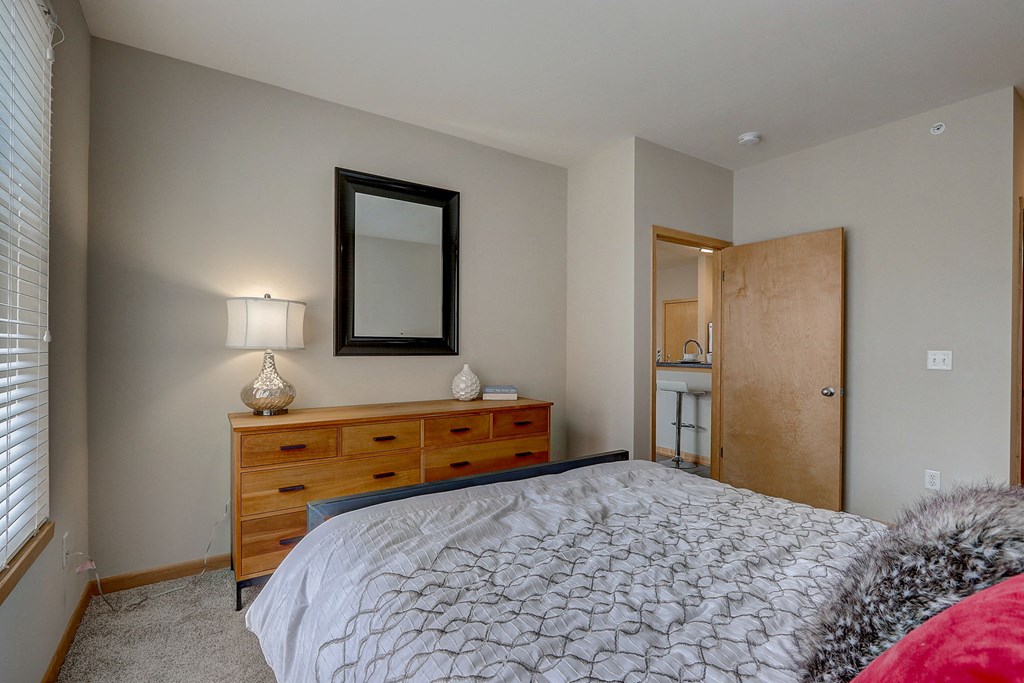 a bedroom with a bed and a dresser with a mirror