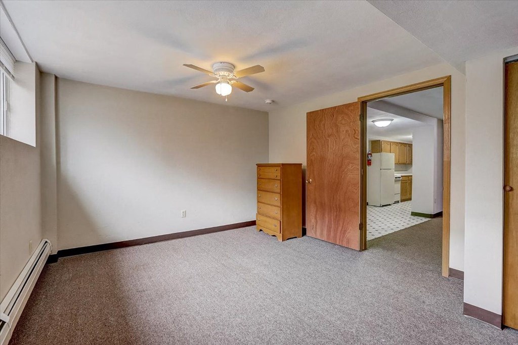 an empty living room with a ceiling fan and a closet