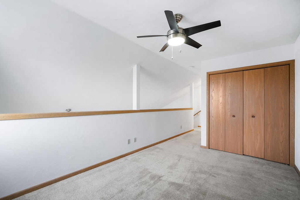 a living room with white walls and a ceiling fan