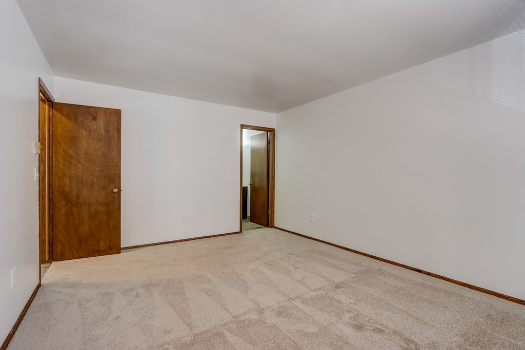 a bedroom with white walls and a wooden door