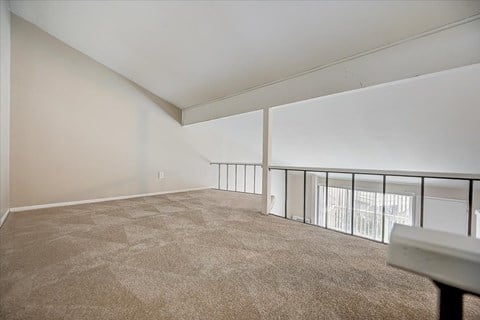 the living room of an apartment with carpet and a balcony