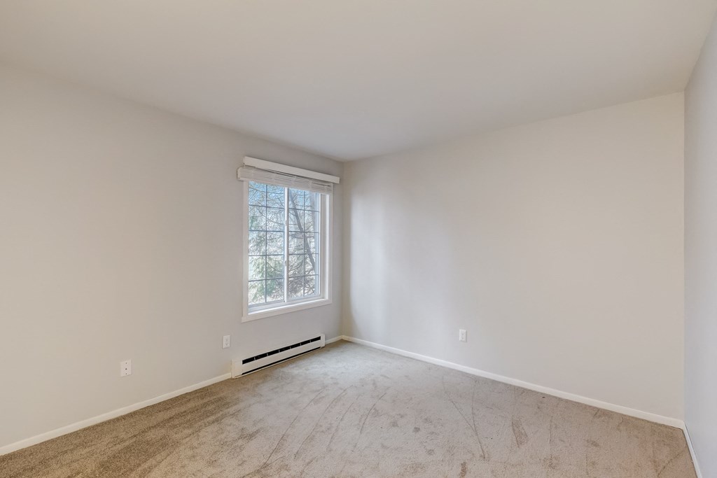 a bedroom with white walls and a window