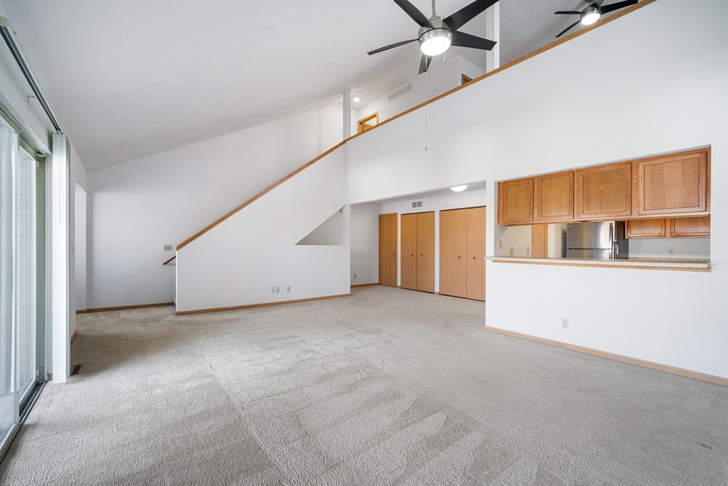 an empty living room with white walls and a ceiling fan