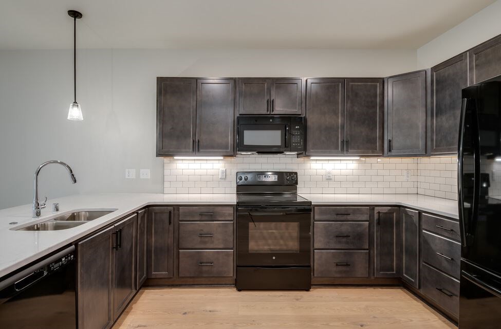 A kitchen with dark wood cabinets and a black oven.