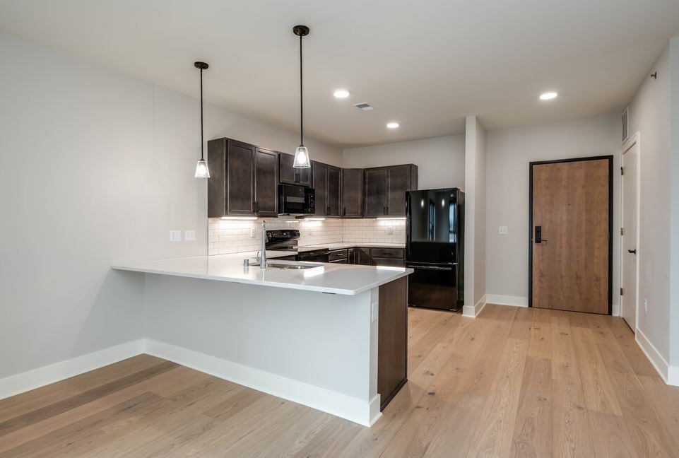 A modern kitchen with a wooden floor and a white countertop.