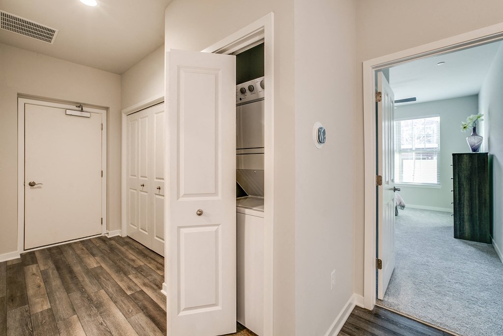 a closet with an open door and a hallway with a door to a laundry room