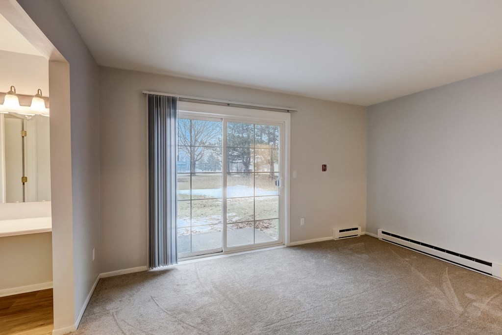 a bedroom with a sliding glass door and a view of a yard