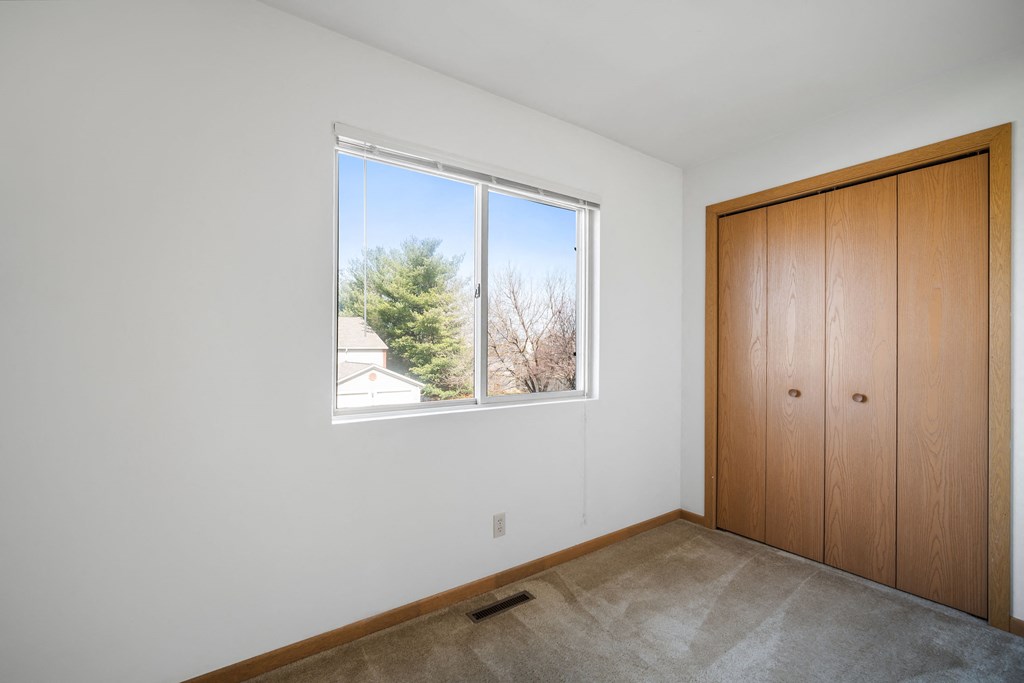 a bedroom with a large window and a closet