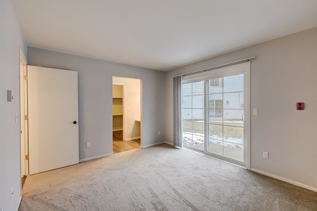a bedroom with a sliding glass door and a door to a walk in closet