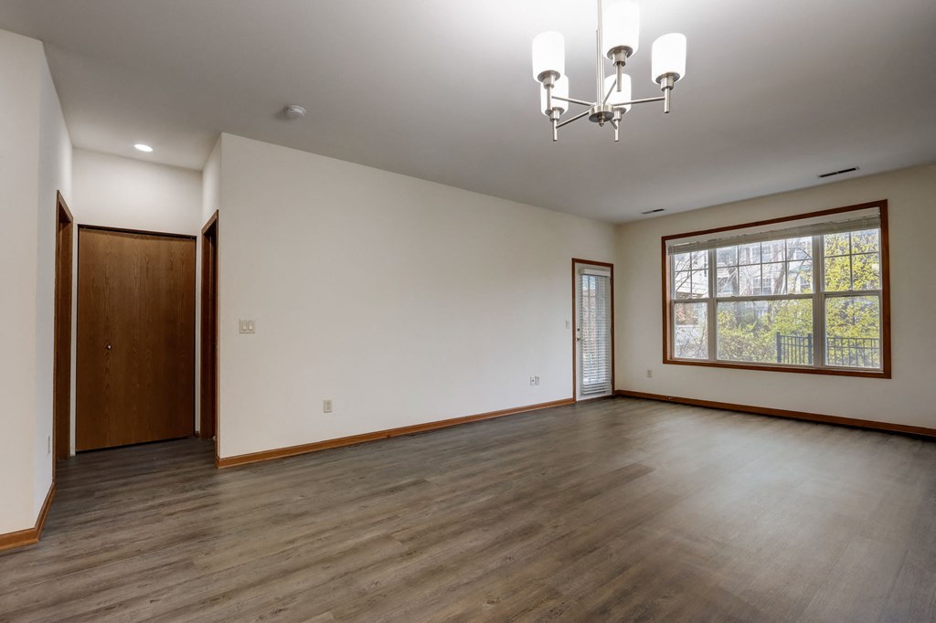 the living room of an empty house with wood floors and white walls