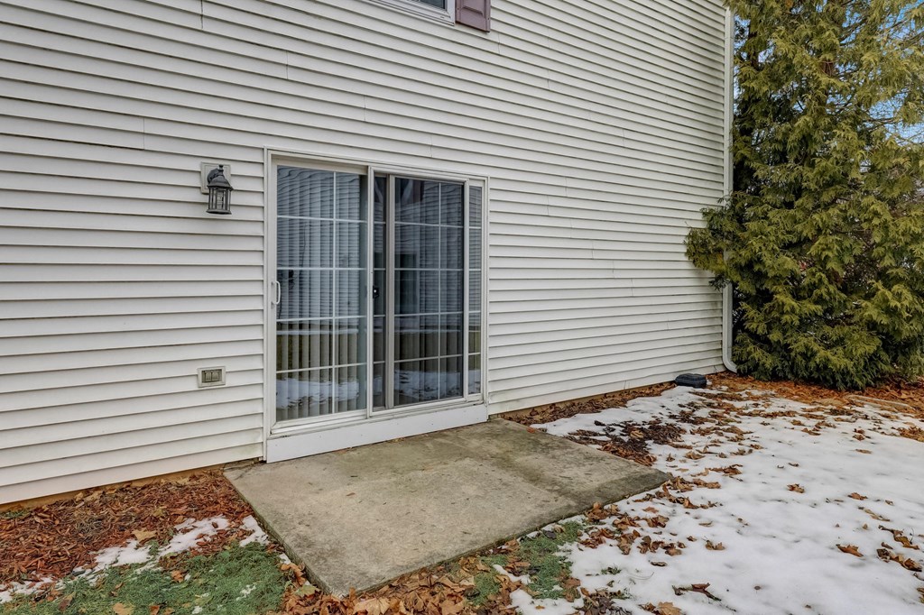 a patio in front of a white house with snow on the ground