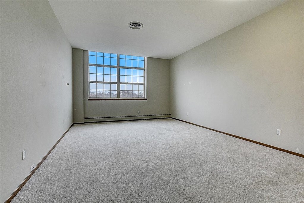 an empty living room with a window and carpet