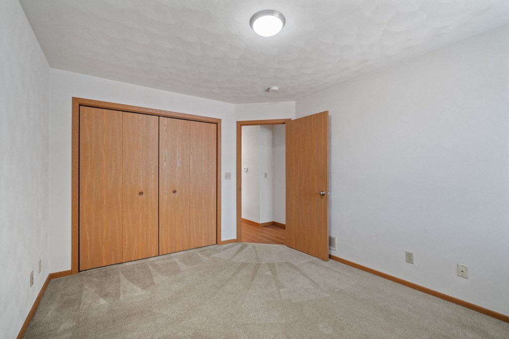 an empty living room with carpet and wood doors