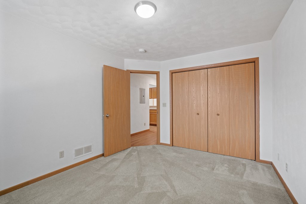 a living room with a carpeted floor and a door to a hallway with a