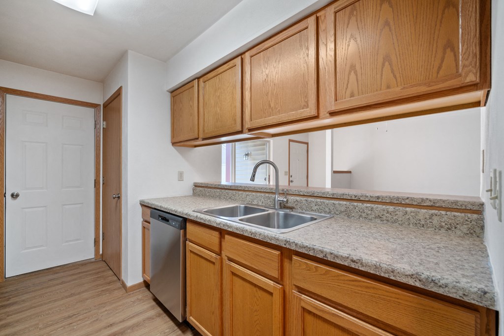 an empty kitchen with wooden cabinets and a stainless steel sink