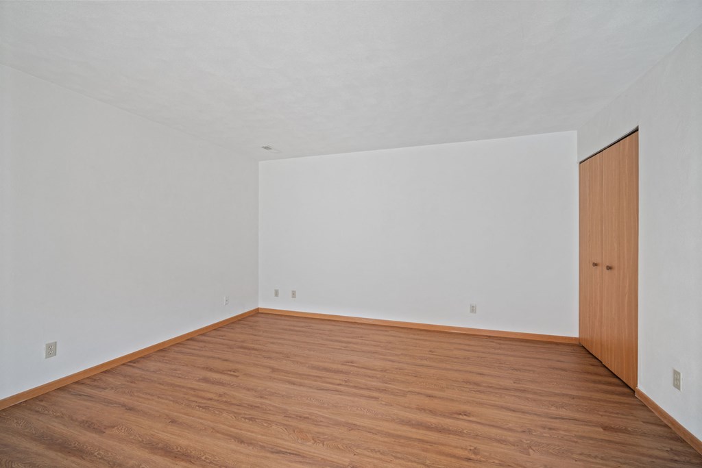 an empty room with wood floors and white walls