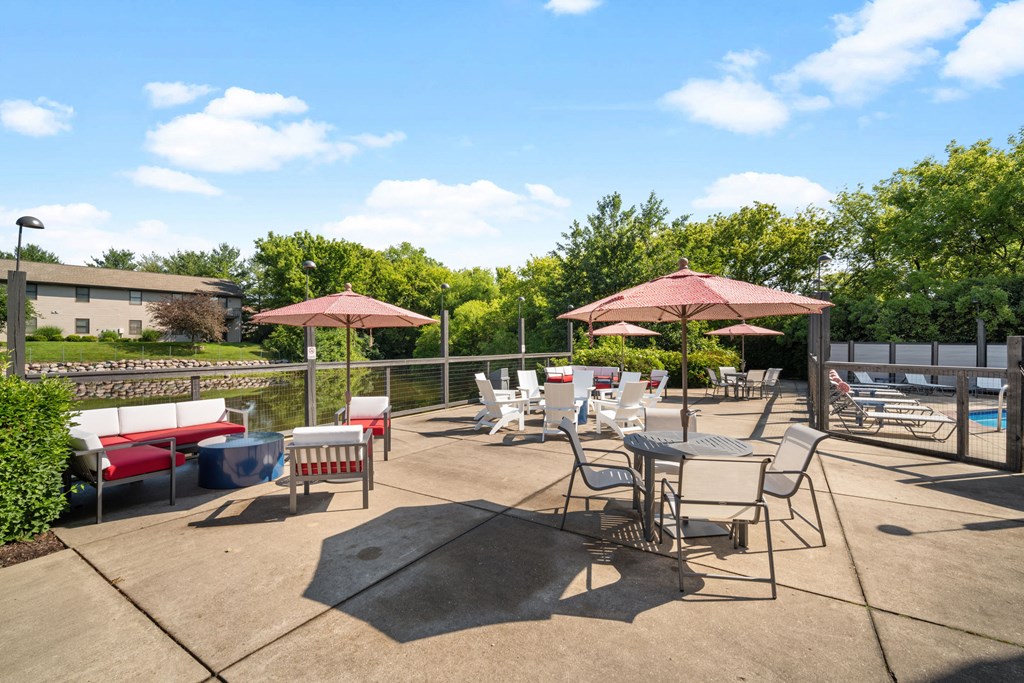 a patio with tables chairs and umbrellas and a pool