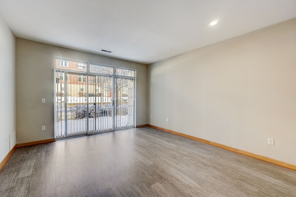 an empty living room with a sliding glass door to a balcony