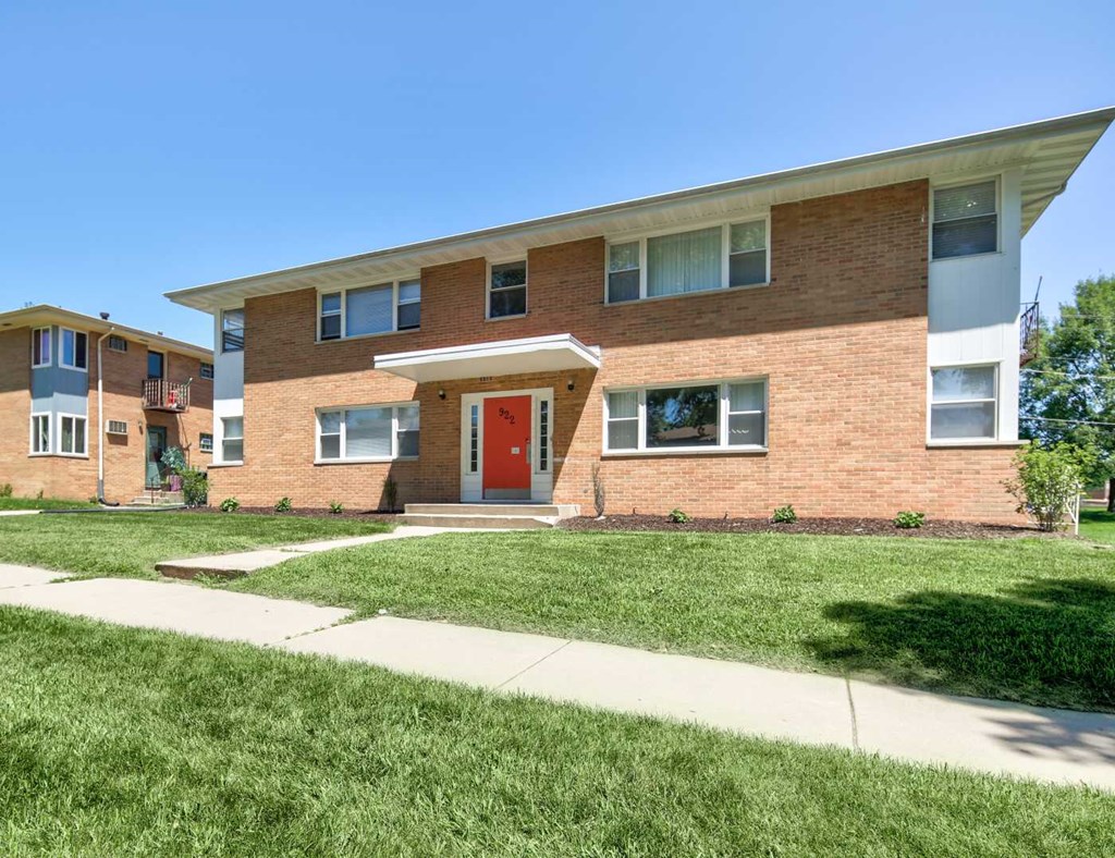 the front of a brick apartment building with a red door