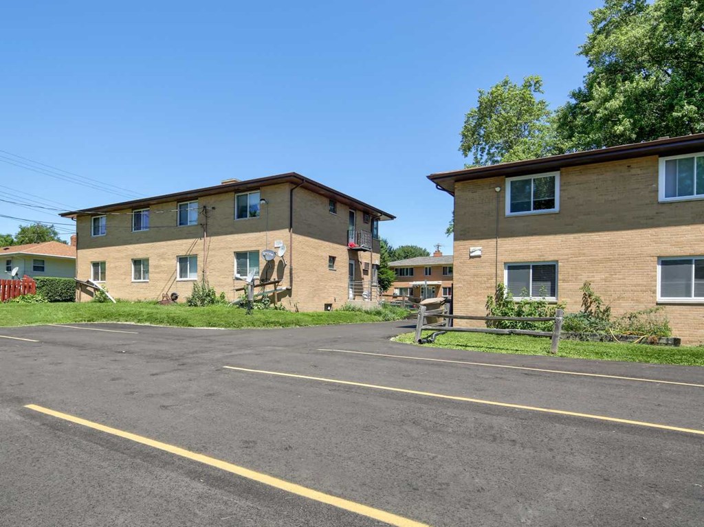 an empty street in front of two brick apartment buildings