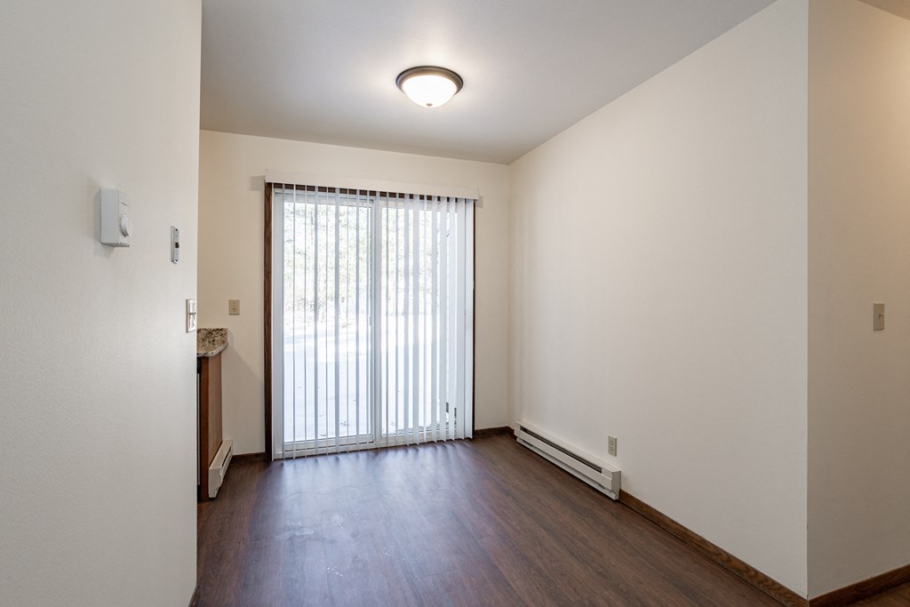 an empty living room with wood floors and a sliding glass door
