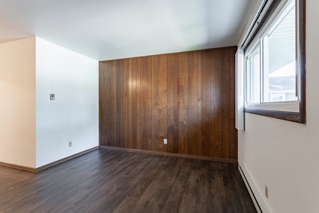 an empty room with wood flooring and a window