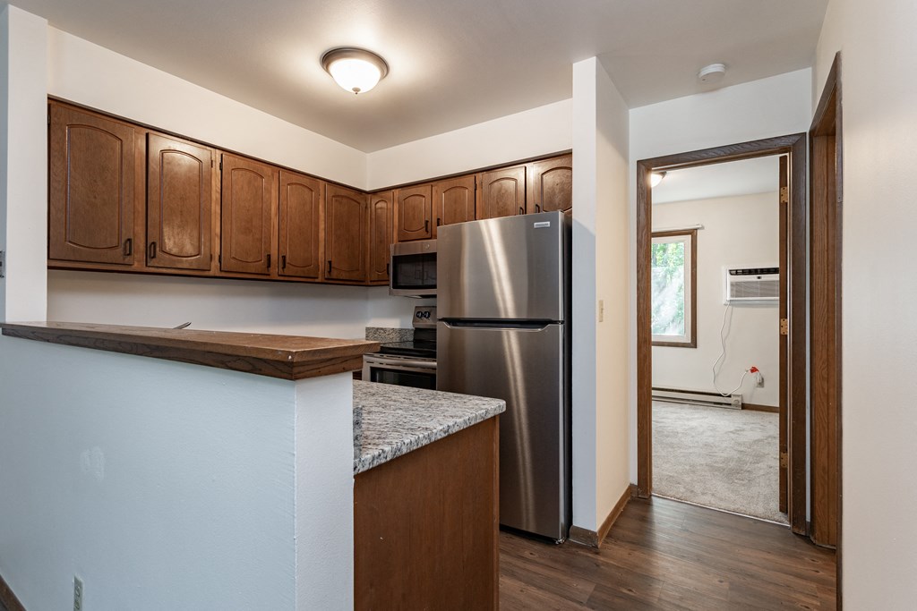 a kitchen with wooden cabinets and a stainless steel refrigerator
