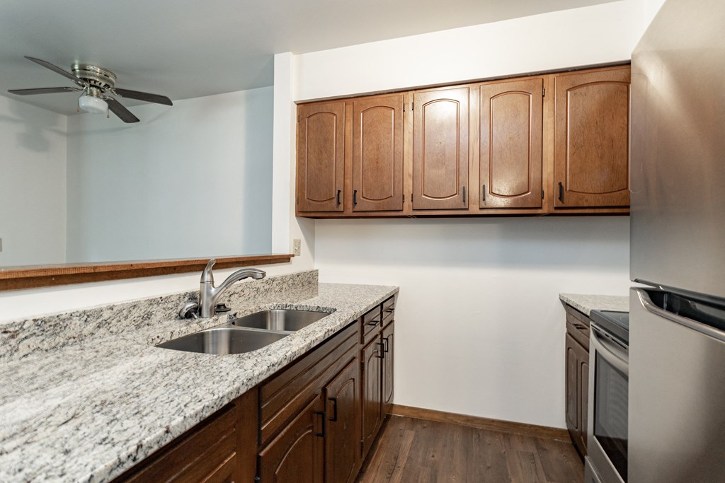 an empty kitchen with granite counter tops and a stainless steel refrigerator
