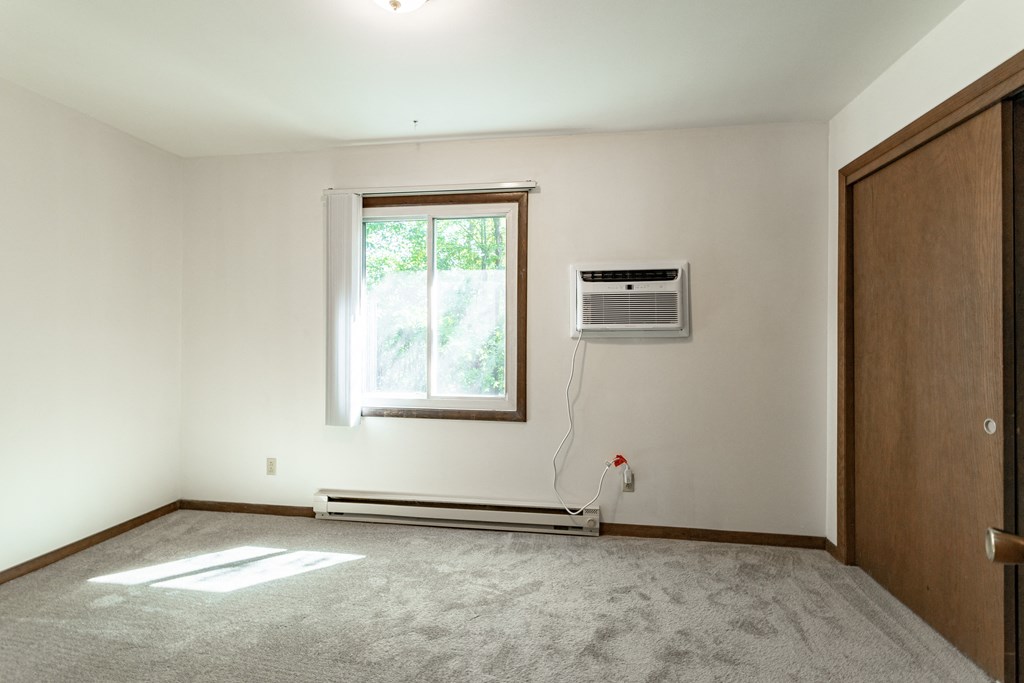 an empty room with a window and an air conditioner