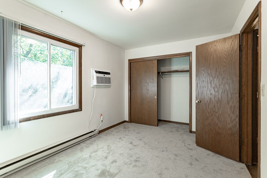 an empty living room with a large window and a door to a closet