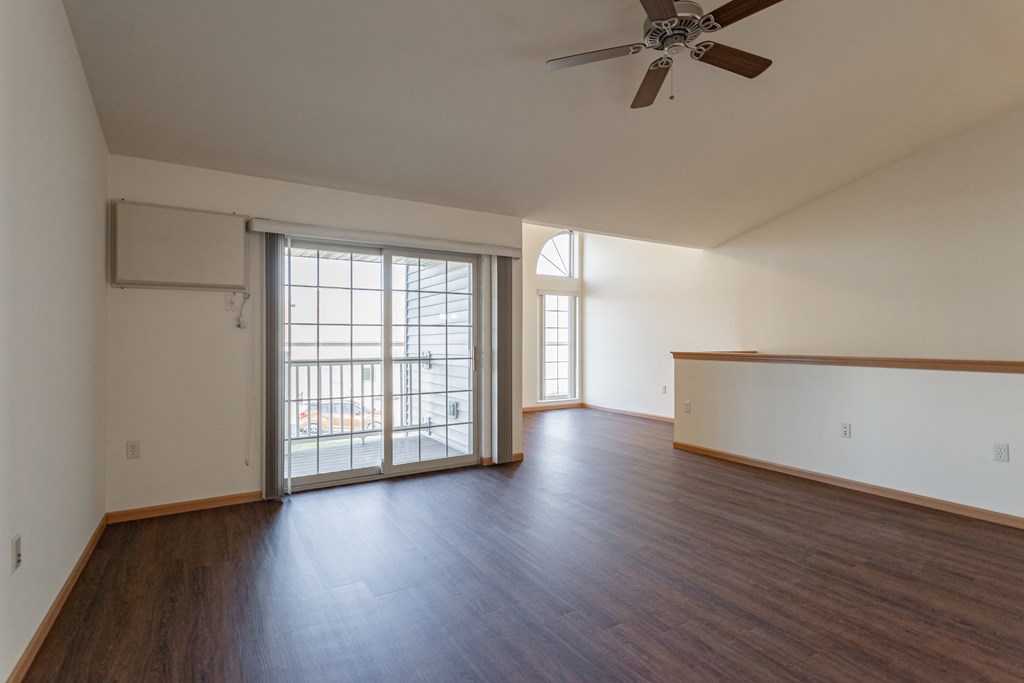 an empty living room with wood floors and a sliding glass door