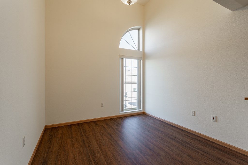 the living room of an empty house with wood flooring and a window