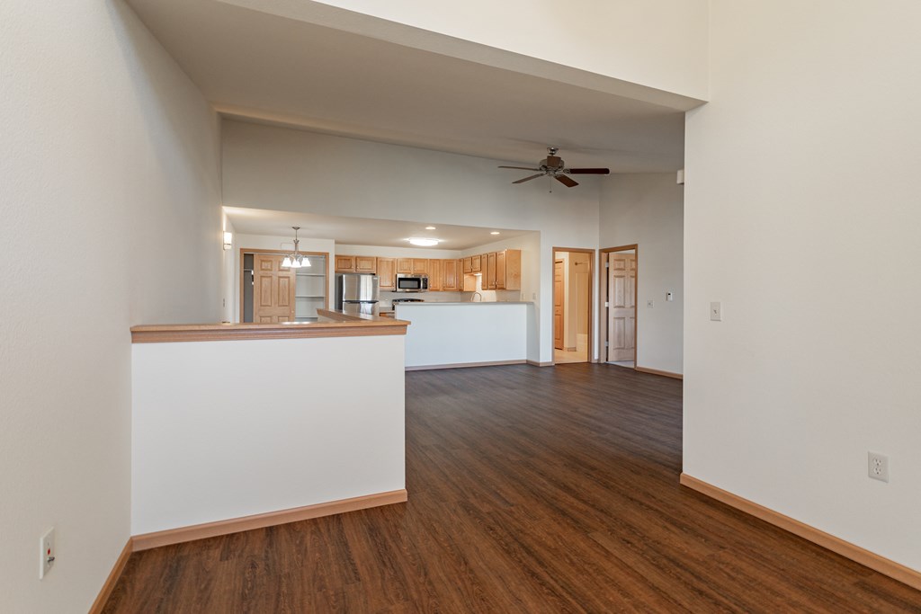 an empty living room and kitchen with a ceiling fan