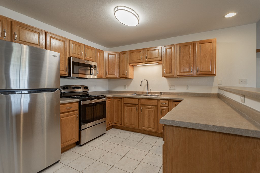 an empty kitchen with wooden cabinets and stainless steel appliances