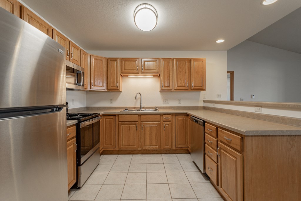 an empty kitchen with wooden cabinets and stainless steel appliances