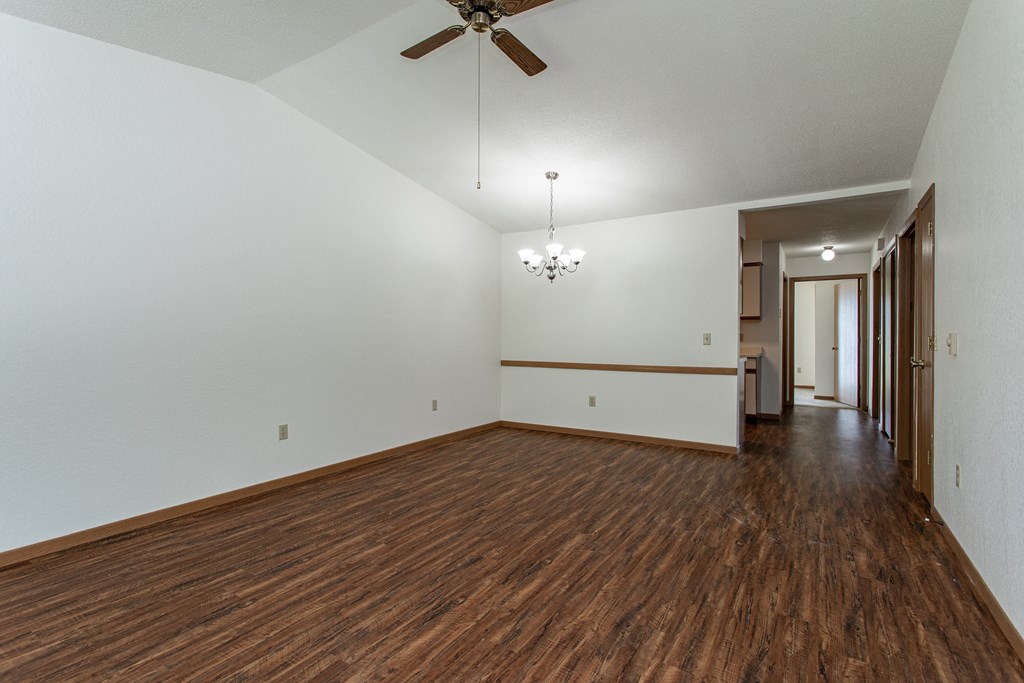an empty living room with wood flooring and a ceiling fan