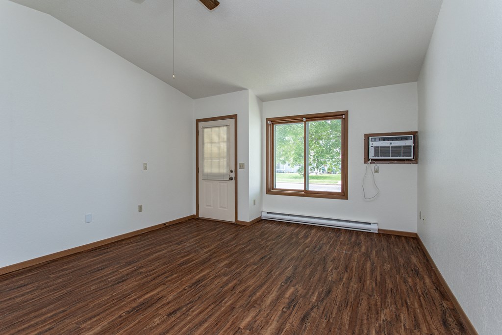 an empty living room with wood flooring and a window