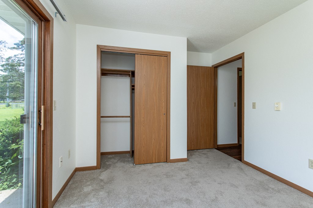 an empty room with a door to a closet and a window