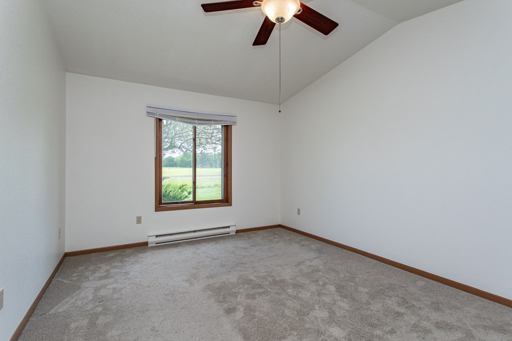 an empty living room with a ceiling fan and a window