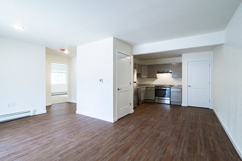 an empty living room and kitchen with wood flooring