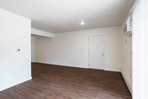 an empty living room with wood flooring and white walls