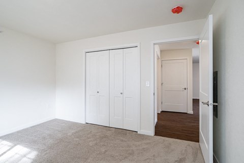 a bedroom with white closets and a carpeted floor