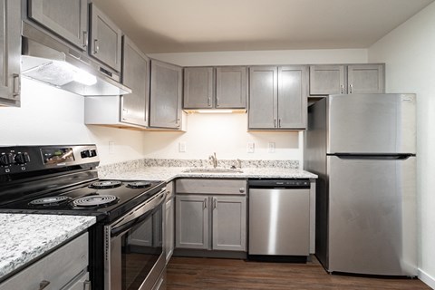 an empty kitchen with stainless steel appliances and granite counter tops