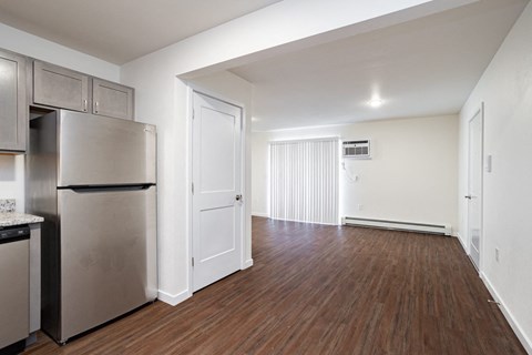 the living room of an apartment with a stainless steel refrigerator and