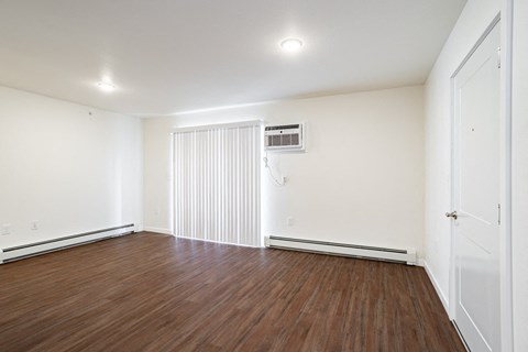 an empty living room with wood floors and white walls