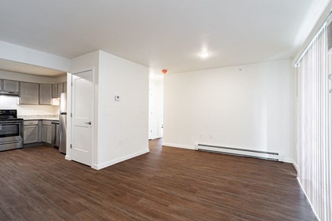 a living room and kitchen with white walls and wood floors