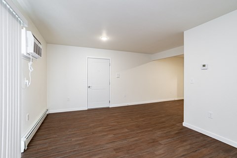 an empty living room with wood flooring and white walls